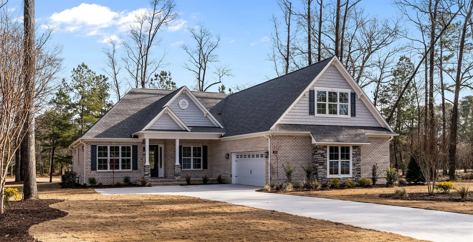 Modern brick house with a gabled roof, surrounded by trees on a neatly landscaped yard. Ideal work of a skilled home builder.