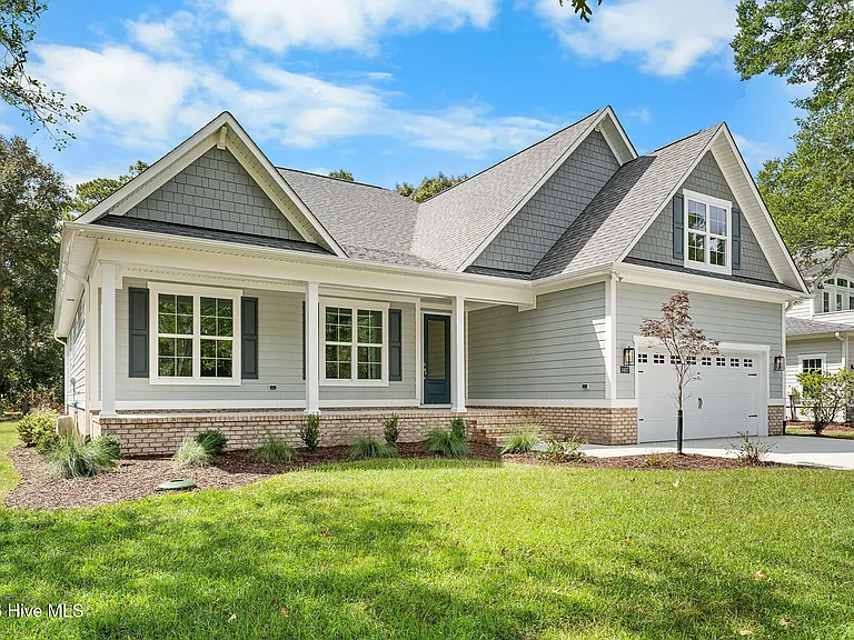 Single-story, blue-gray home with gabled roof, manicured lawn, and spacious garage, showcasing modern home builder design.